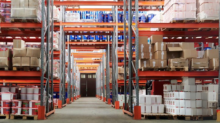 Spacious warehouse filled with numerous red storage racks containing boxes with goods.